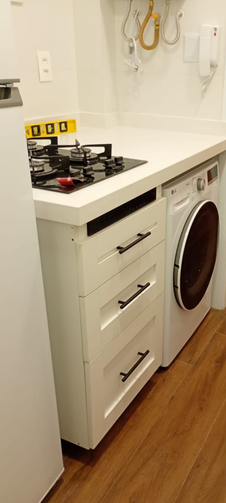 Bancada de cozinha branca com cooktop e máquina de lavar