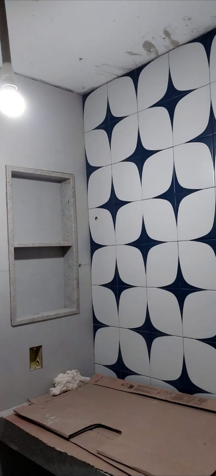 Banheiro com azulejos azul e branco e nicho de gesso